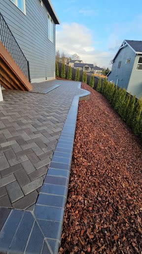 Herringbone paver patio with mulch borders and arborvitae